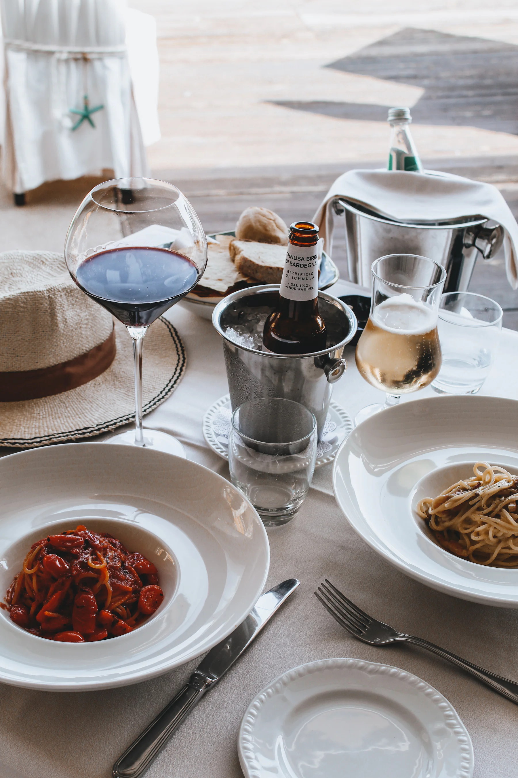 Gedeckter Tisch mit Pasta, Rotwein und Weinflasche